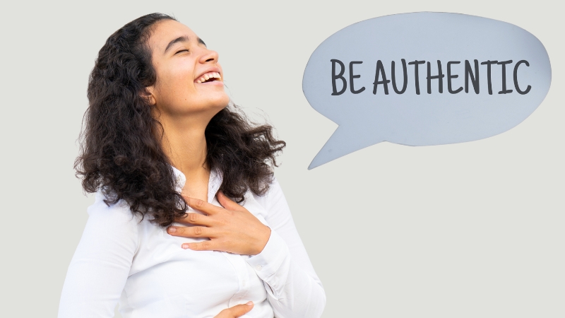 A smiling woman holds her hand to her chest with a speech bubble beside her that says “Be Authentic.”