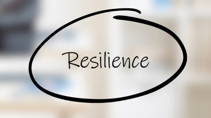 A handwritten word “Resilience” is circled in black on a blurred light background